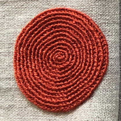 Close up of embroidered orange circle on linen serviette