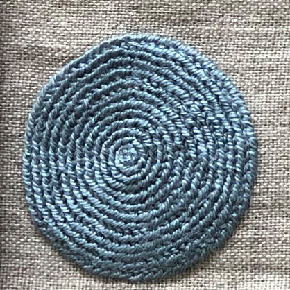 Close up of embroidered circle in sky blue on natural linen serviette