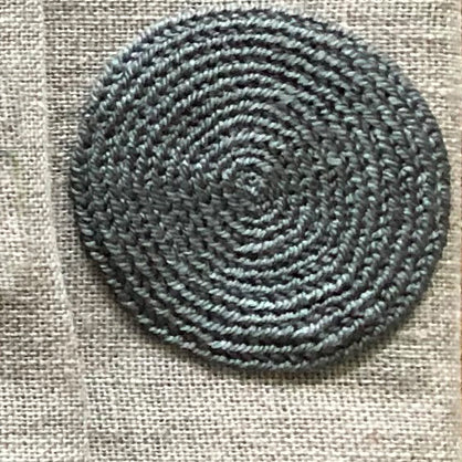 Grey embroidered circle on white linen table napkin