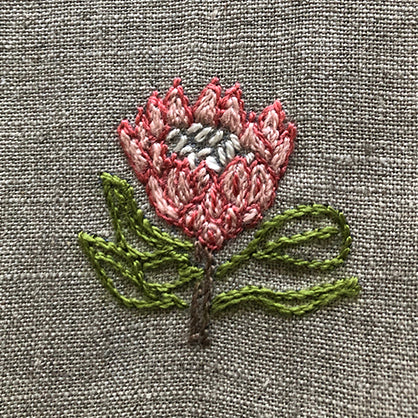 King protea embroidered on a linen table napkin