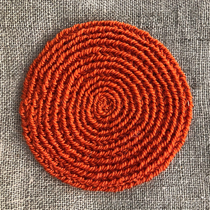 Close up of hand embroidered orange circle on natural linen table napkin